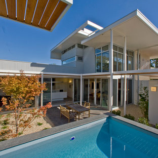 Inredning av en modern mellanstor rektangulär träningspool på baksidan av huset, med grus