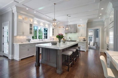 Photo of a large transitional u-shaped separate kitchen in Dallas with an undermount sink, recessed-panel cabinets, white cabinets, marble benchtops, multi-coloured splashback, ceramic splashback, panelled appliances, medium hardwood floors, with island, brown floor and white benchtop.