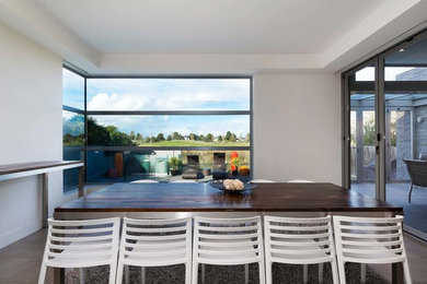 Large contemporary open plan dining in Melbourne with white walls and beige floor.