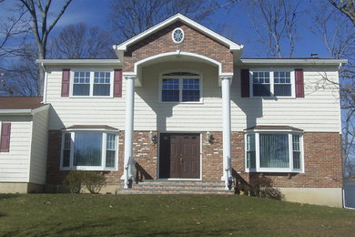 This is an example of a mid-sized traditional two-storey multi-coloured house exterior in New York with vinyl siding, a gable roof and a shingle roof.