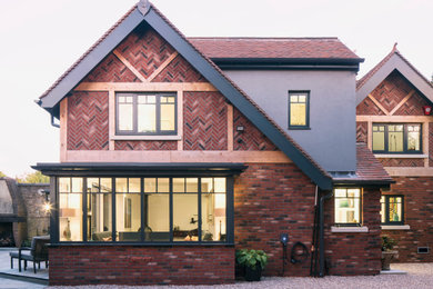 Idee per la villa rossa classica a due piani con rivestimento in mattoni, copertura in tegole e tetto rosso