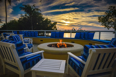 Inspiration for a mid-sized tropical backyard stone patio remodel in Miami with a fire pit and no cover