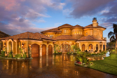 Inspiration for a huge mediterranean yellow two-story stucco house exterior remodel in Los Angeles with a hip roof and a tile roof