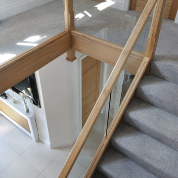 Modern staircase with a mix of glass and natural oak and carpeted treads