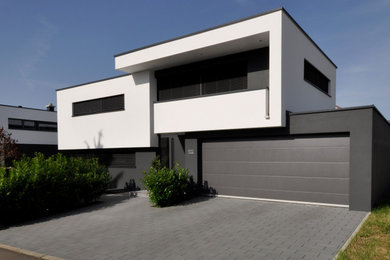 Imagen de fachada de casa blanca minimalista de dos plantas con revestimiento de estuco y tejado plano