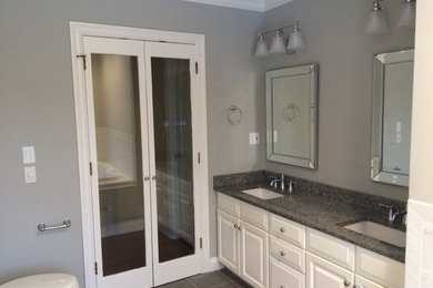 Large elegant master ceramic tile ceramic tile corner bathtub photo in Boston with raised-panel cabinets, white cabinets, a two-piece toilet, gray walls, an undermount sink and granite countertops