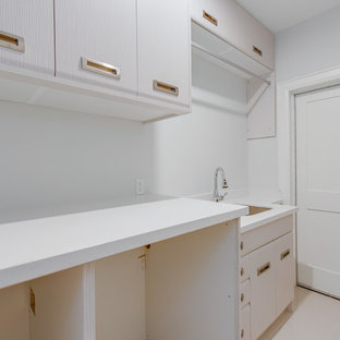 トロントの小さいモダンスタイルのおしゃれな家事室 (アンダーカウンターシンク、フラットパネル扉のキャビネット、ステンレスキャビネット、クオーツストーンカウンター、白い壁、磁器タイルの床、左右配置の洗濯機・乾燥機、白い床、白いキッチンカウンター) の写真