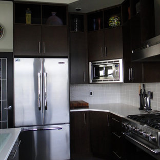 Inredning av ett modernt mycket stort kök, med släta luckor, skåp i mörkt trä, bänkskiva i kvarts, gult stänkskydd, stänkskydd i glaskakel, rostfria vitvaror, klinkergolv i keramik och flera köksöar