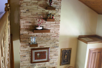 Mid-sized mountain style loft-style medium tone wood floor living room photo in Indianapolis with beige walls, a standard fireplace, a stone fireplace and no tv