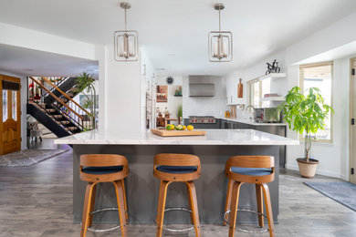 Inspiration for a mid-sized modern u-shaped vinyl floor and gray floor eat-in kitchen remodel in Los Angeles with an undermount sink, shaker cabinets, white cabinets, quartz countertops, white backsplash, marble backsplash, stainless steel appliances, an island and white countertops