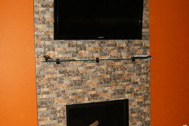 Example of a mid-sized classic enclosed medium tone wood floor and brown floor living room design in New York with orange walls, a standard fireplace and a stone fireplace