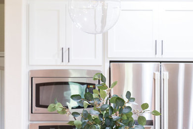 Inspiration for a cottage medium tone wood floor and brown floor eat-in kitchen remodel in Other with shaker cabinets, white cabinets, wood countertops, white backsplash, subway tile backsplash, stainless steel appliances and an island