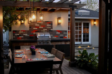 Inspiration for a mid-sized transitional backyard and ground level deck in Los Angeles with a container garden and a pergola.