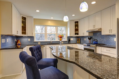 Photo of a contemporary u-shaped kitchen pantry in DC Metro with an integrated sink, recessed-panel cabinets, white cabinets, granite benchtops, blue splashback, glass tile splashback, stainless steel appliances, travertine floors and with island.