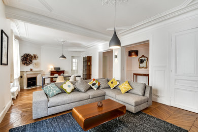 This is an example of a large contemporary enclosed family room in Paris with white walls, medium hardwood floors and no tv.