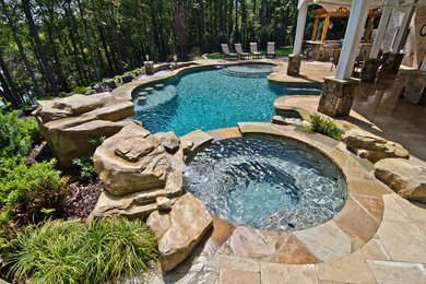 Design ideas for a large transitional backyard custom-shaped pool in Other with a hot tub and tile.
