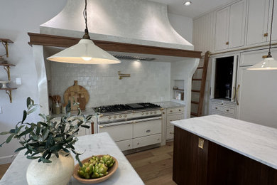 Eat-in kitchen - mid-sized french country galley light wood floor eat-in kitchen idea in Portland with a farmhouse sink, beaded inset cabinets, white cabinets, marble countertops, beige backsplash, ceramic backsplash, two islands and white countertops