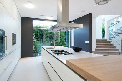 Trendy ceramic tile kitchen photo in Orange County with a drop-in sink, flat-panel cabinets, white cabinets, granite countertops, white backsplash, white appliances and an island