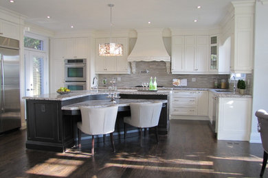 Photo of a mid-sized transitional u-shaped open plan kitchen in Toronto with a single-bowl sink, recessed-panel cabinets, white cabinets, stainless steel appliances, dark hardwood floors and with island.
