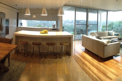 This is an example of a mid-sized modern u-shaped eat-in kitchen in Sydney with an undermount sink, white cabinets, quartz benchtops, glass sheet splashback, stainless steel appliances, travertine floors and with island.