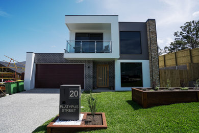 Diseño de fachada de casa multicolor y blanca moderna de dos plantas con revestimiento de ladrillo, tejado plano y tejado de metal