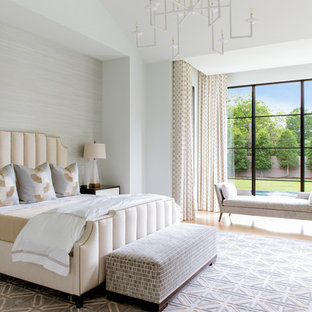 Large mediterranean master bedroom in Dallas with light hardwood flooring and grey walls.