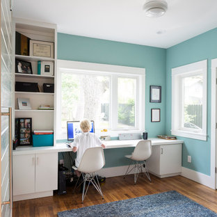 Inspiration för små klassiska hemmabibliotek, med ett inbyggt skrivbord, blå väggar, mellanmörkt trägolv och brunt golv