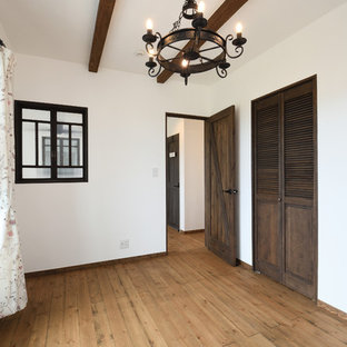 Idee per una grande camera matrimoniale etnica con pareti bianche, pavimento in legno massello medio, nessun camino, cornice del camino in legno e pavimento marrone