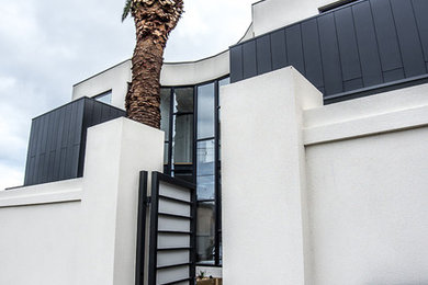 This is an example of a mid-sized contemporary two-storey stucco white exterior in Melbourne with a flat roof.
