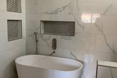 Modelo de cuarto de baño contemporáneo de tamaño medio con bañera exenta, paredes blancas y suelo gris