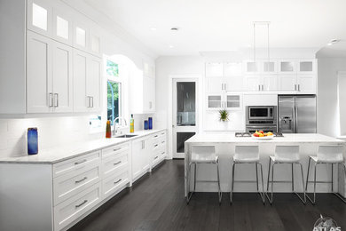 Eat-in kitchen - large contemporary l-shaped dark wood floor eat-in kitchen idea in Vancouver with an undermount sink, shaker cabinets, white cabinets, quartzite countertops, white backsplash, porcelain backsplash, stainless steel appliances and an island