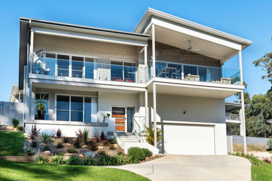 Photo of a beach style two-storey white house exterior in Central Coast with painted brick siding.
