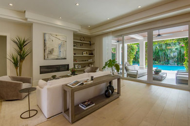 Large trendy formal and loft-style light wood floor, beige floor and wallpaper living room photo in Miami with beige walls, a standard fireplace and a metal fireplace