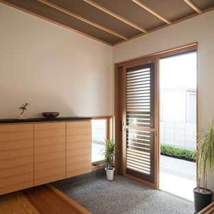 Idee per un ingresso o corridoio etnico con pareti bianche, una porta scorrevole e pavimento marrone