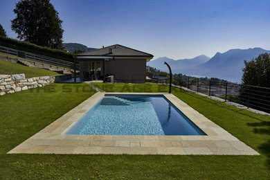 Immagine di una piscina naturale minimal rettangolare di medie dimensioni e davanti casa con una vasca idromassaggio e pavimentazioni in pietra naturale