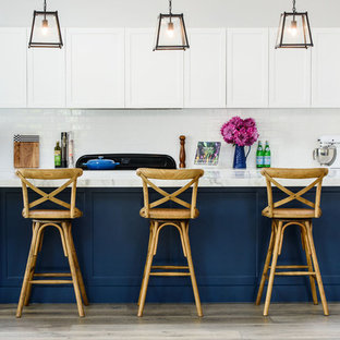 メルボルンのトランジショナルスタイルのおしゃれなキッチン (シェーカースタイル扉のキャビネット、白いキャビネット、白いキッチンパネル、サブウェイタイルのキッチンパネル、シルバーの調理設備の、淡色無垢フローリング、ベージュの床) の写真