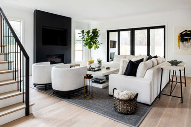 Contemporary living room in DC Metro with white walls, light hardwood floors, a ribbon fireplace, a wall-mounted tv and beige floor.