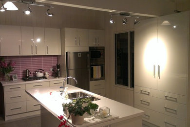 Example of a mid-sized trendy galley ceramic tile eat-in kitchen design in Wollongong with an undermount sink, flat-panel cabinets, white cabinets, quartz countertops, pink backsplash, ceramic backsplash, stainless steel appliances and an island