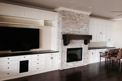 Family room - large transitional open concept dark wood floor and brown floor family room idea in Tampa with beige walls, a standard fireplace, a stacked stone fireplace and a wall-mounted tv