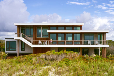 This is an example of a large modern split-level brown house exterior in Other with wood siding, a flat roof and shingle siding.