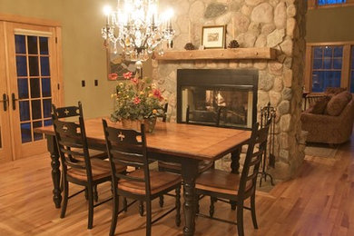 Inspiration for a mid-sized rustic kitchen/dining room combo remodel in Other with green walls, a two-sided fireplace and a stone fireplace