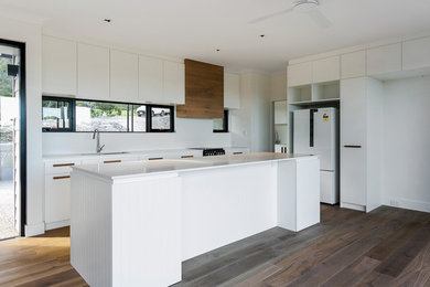 Inspiration for a mid-sized modern single-wall open plan kitchen in Adelaide with a drop-in sink, white cabinets, granite benchtops, window splashback, stainless steel appliances, medium hardwood floors, with island, brown floor and white benchtop.