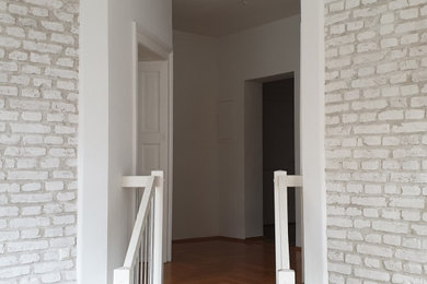 ミュンヘンにある高級な中くらいな北欧スタイルのおしゃれな玄関ロビー (白い壁、レンガ壁) の写真