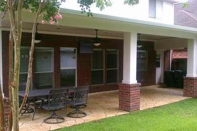 Mid-sized elegant backyard stamped concrete patio photo in Houston with a roof extension