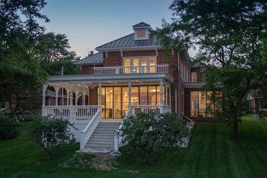 Example of a large classic red three-story brick house exterior design in Toronto with a metal roof