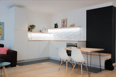 Mid-sized contemporary l-shaped open plan kitchen in Lille with a single-bowl sink, beaded inset cabinets, white cabinets, wood benchtops, white splashback, ceramic splashback, panelled appliances and beige benchtop.