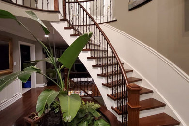Diseño de escalera curva de tamaño medio con escalones de madera, contrahuellas de madera y barandilla de varios materiales