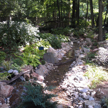 Shady Backyard with Waterfall, Stream, Fireplace and Landscape