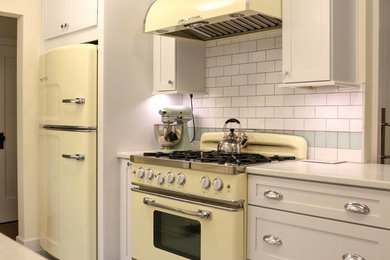 Example of a large classic u-shaped linoleum floor enclosed kitchen design in Portland with a farmhouse sink, shaker cabinets, white cabinets, quartz countertops, white backsplash, subway tile backsplash, colored appliances and a peninsula