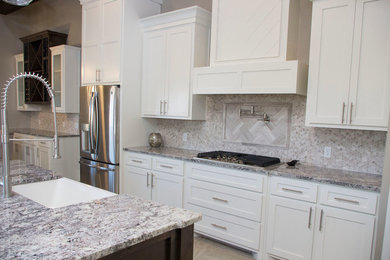 Elegant ceramic tile kitchen photo in Austin with a farmhouse sink, flat-panel cabinets, white cabinets, granite countertops, gray backsplash, ceramic backsplash and stainless steel appliances